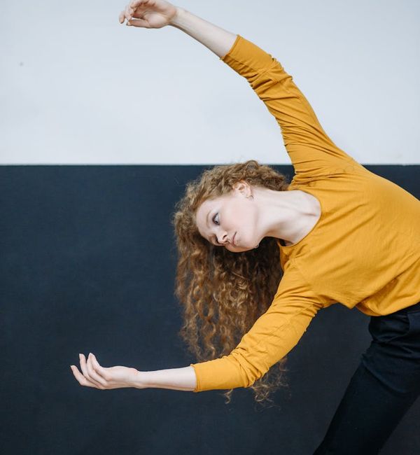 Woman in a dynamic and fluid stretching pose in a modern studio.